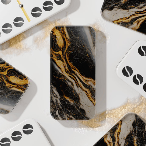Black and gold marble double six dominos on a white and gold marble table. Some of the dominos are face down and some are face up showing the black pips that have a wave within them.